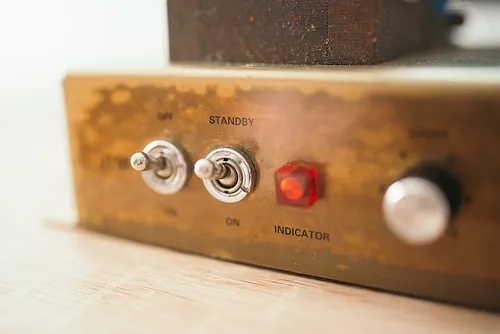 Close-up view of a vintage device's control panel featuring toggle switches labeled on and standby, alongside a red indicator light, showcas